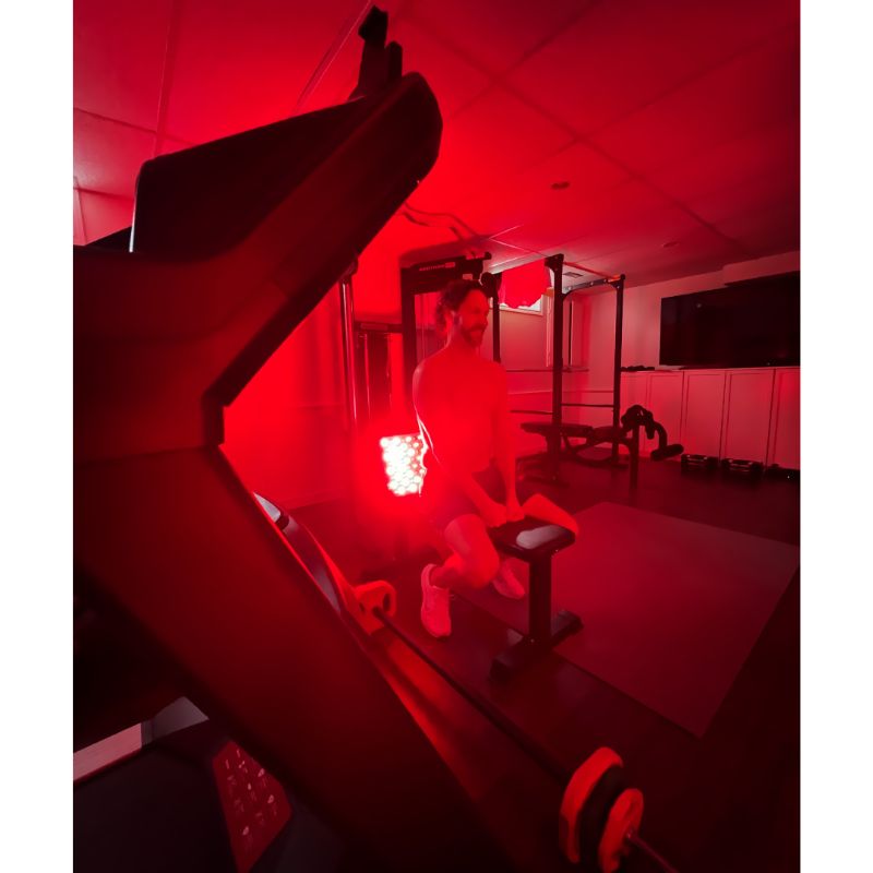Person exercising in a gym with Fringe Red Light Panel