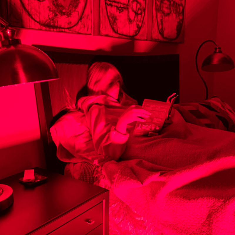 Person lying in bed under a Fringe Red Light Panel